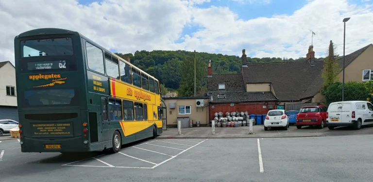 A green double decker bus parked in a bus station