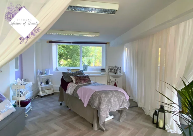 A light room with a bed in the middle with a grey and pink cover
