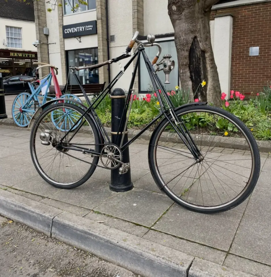 Historic bicycle lent up against a street bollard.